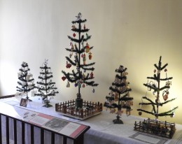 This display of feather trees is decorated with ornaments indicative of different eras in Hermann's Christmas traditions. The first tree on the left has scherenschnitte ornaments that were cut in the 1940's.